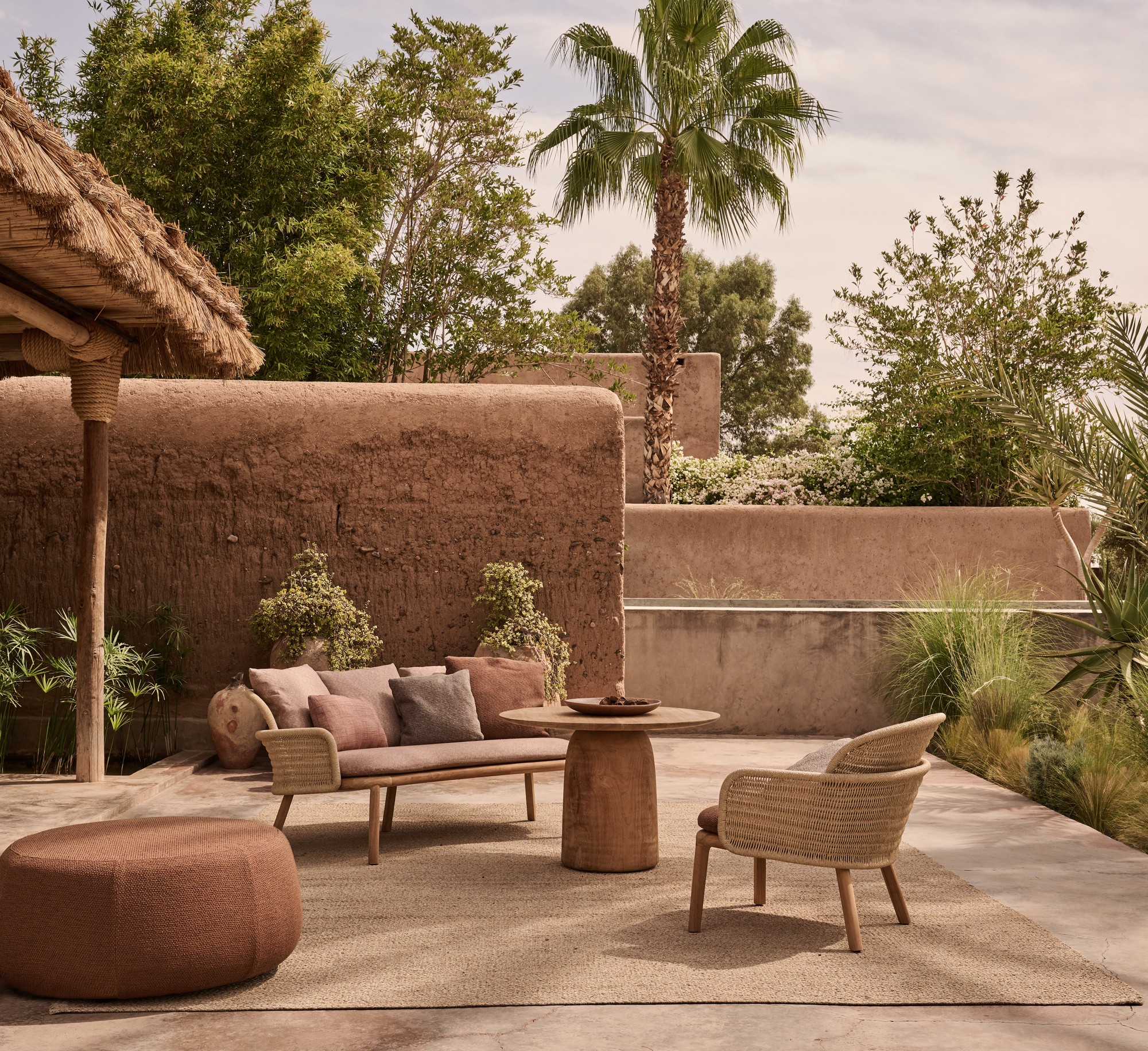 Teak and rope outdoor sofa arranged on a landscaped patio