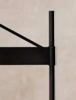 Close-up of the black wall lamp's diagonal brace and stem connection.