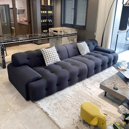Dark Cocoon sofa with rounded tufted cushions and low arms in a living room
