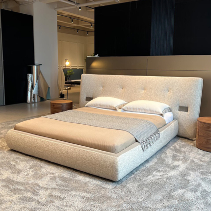 Rever upholstered bed with a wide curved headboard and softly rounded fabric base