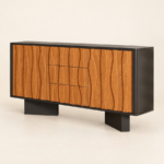 Carved wave-front sideboard with three central drawers, a black frame and two plinth supports on a warm ivory background.