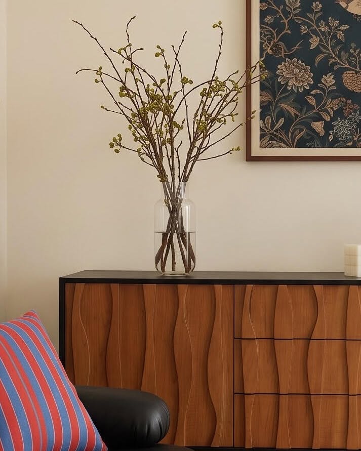 Left side of the wooden sideboard styled with a vase and framed artwork.