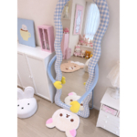 Angled view of the Hug Blue Gingham Floor Mirror with pale-blue padded arms