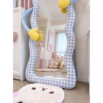 Close detail of the blue-and-white gingham upholstered mirror frame and yellow mitten accent