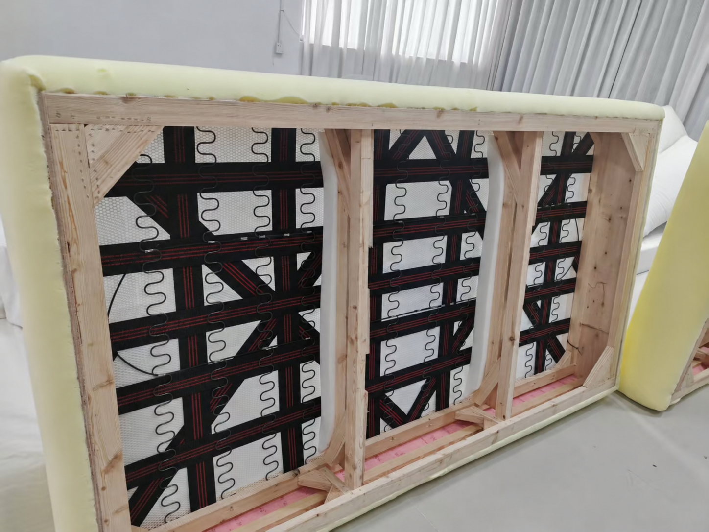 Underside of a BUNISE sofa showing timber framing, zigzag-shaped springs and support webbing.