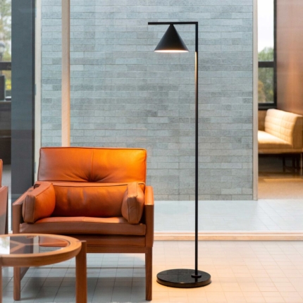 Black floor lamp beside an orange lounge chair in an interior setting