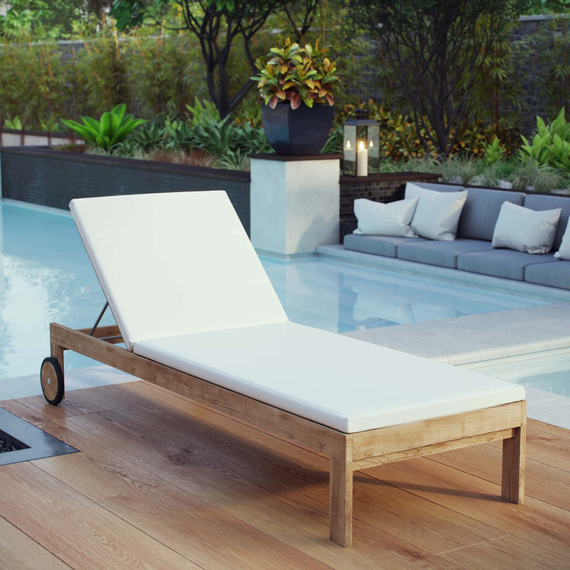 Elvar outdoor chaise with pale cushions on a timber deck beside a pool.