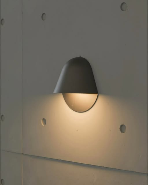 Dark curved wall light casting a warm glow in a BUNISE Instagram photograph