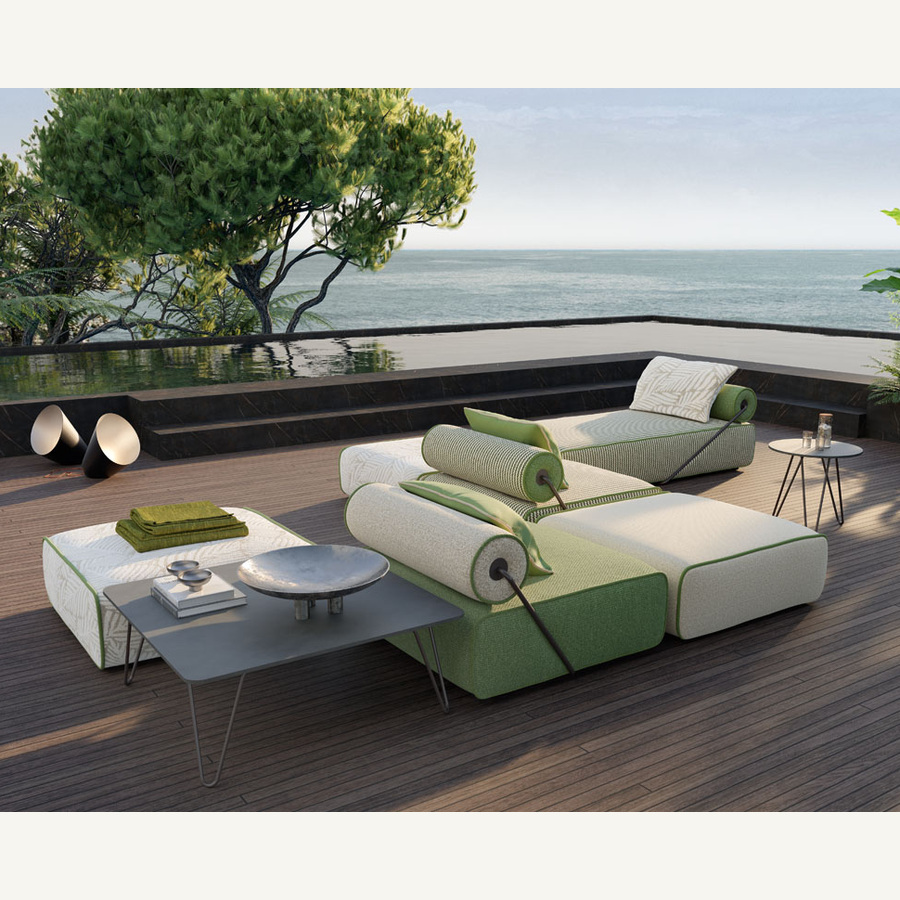 leran-modular-outdoor-sofa-01-main-900 Green and cream modular outdoor sofa with cylindrical back cushions and slim diagonal supports on a sea-facing terrace.