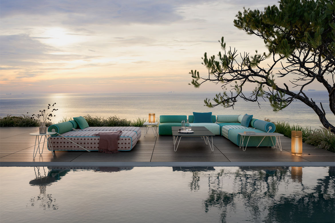 Design reference: Turquoise seating and a patterned chaise arranged beside a reflecting pool at sunset.