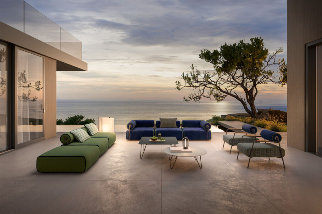 Design reference: Green seating, a dark blue sofa and separate chairs arranged on a sea-facing covered terrace.