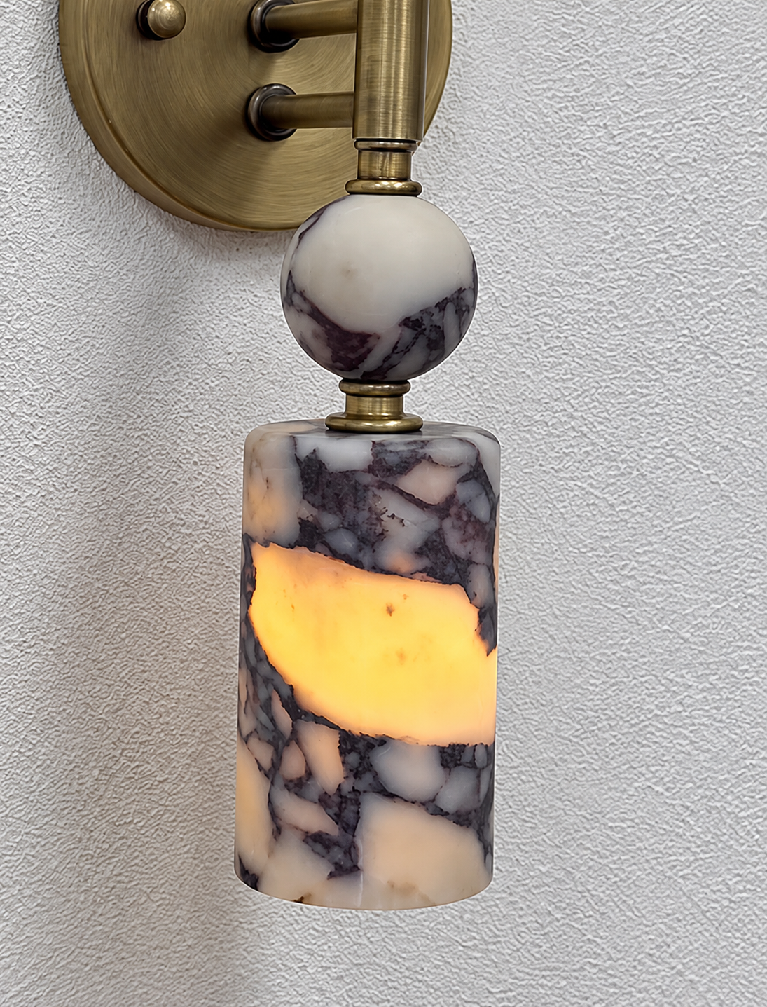 Close-up of the dark veined stone shade and sphere on the Veyra wall lamp