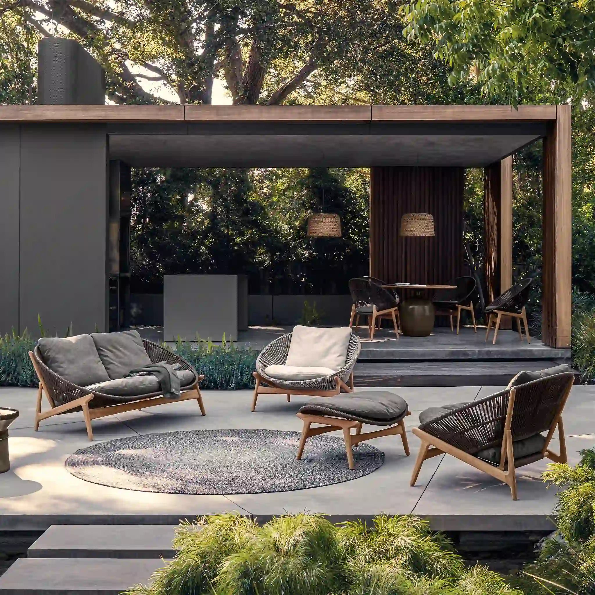 Woven outdoor lounge furniture arranged on a terrace beside a pavilion